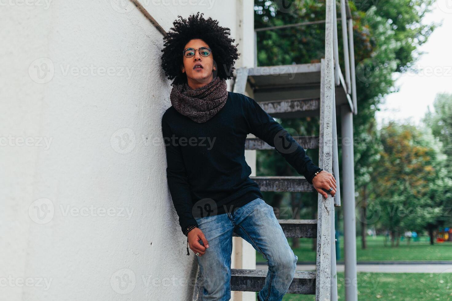 Young Afro american young businessman or student wearing black turtleneck sweater and scarf and having curly dark hair. Concept of stylish and fashionable look photo