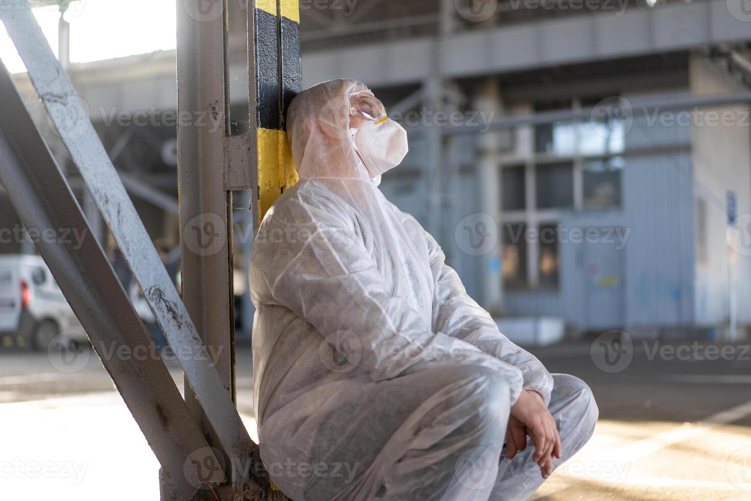 Despair healthcare worker in white covid protective overalls. Tired Male caucasian doctor in depression during coronavirus pandemic photo
