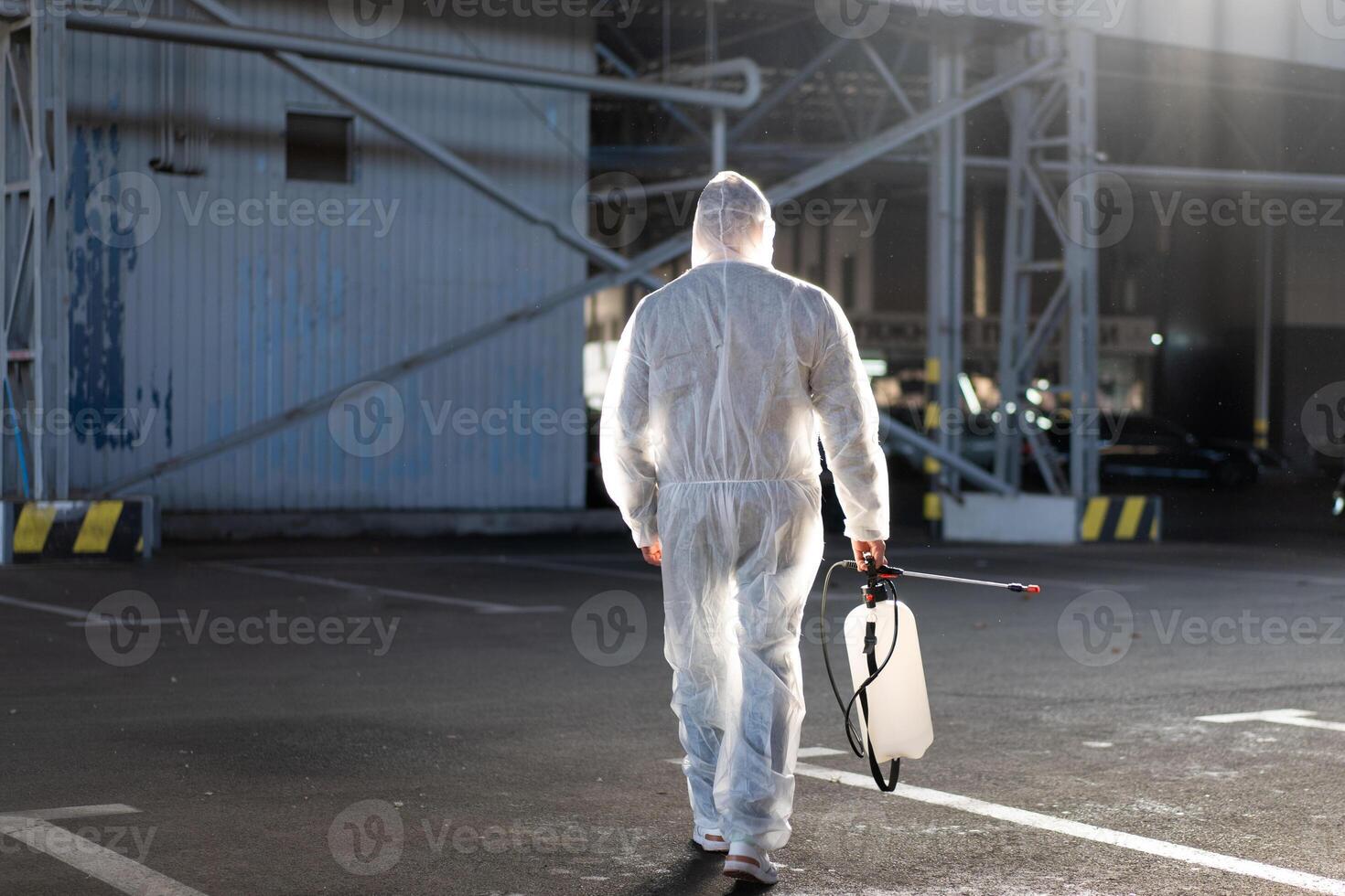 Man dressed white protective overalls spraying surface antibacterial sanitizer sprayer during quarantine photo