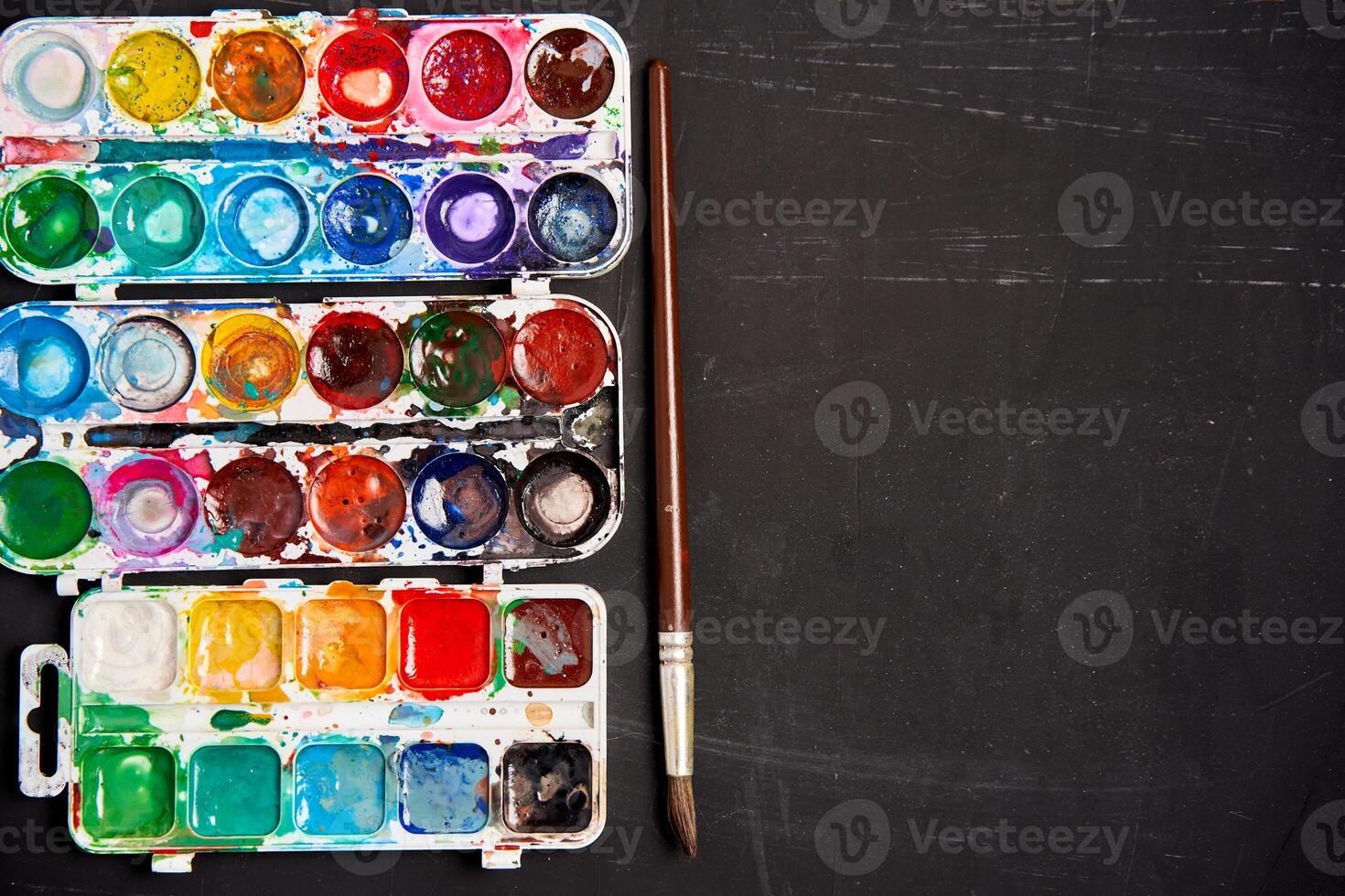 Set of watercolor paints on a black background. Brushes drawing. Creative background. School for teaching drawing. photo