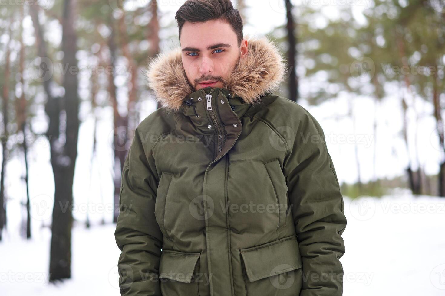 Attractive bearded man standing outdoors in winter season forest. photo