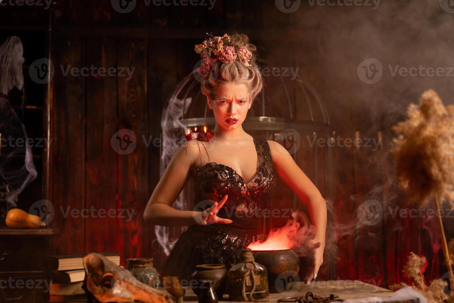 Halloween Witch with cauldron. Beautiful young woman conjuring, making witchcraft photo