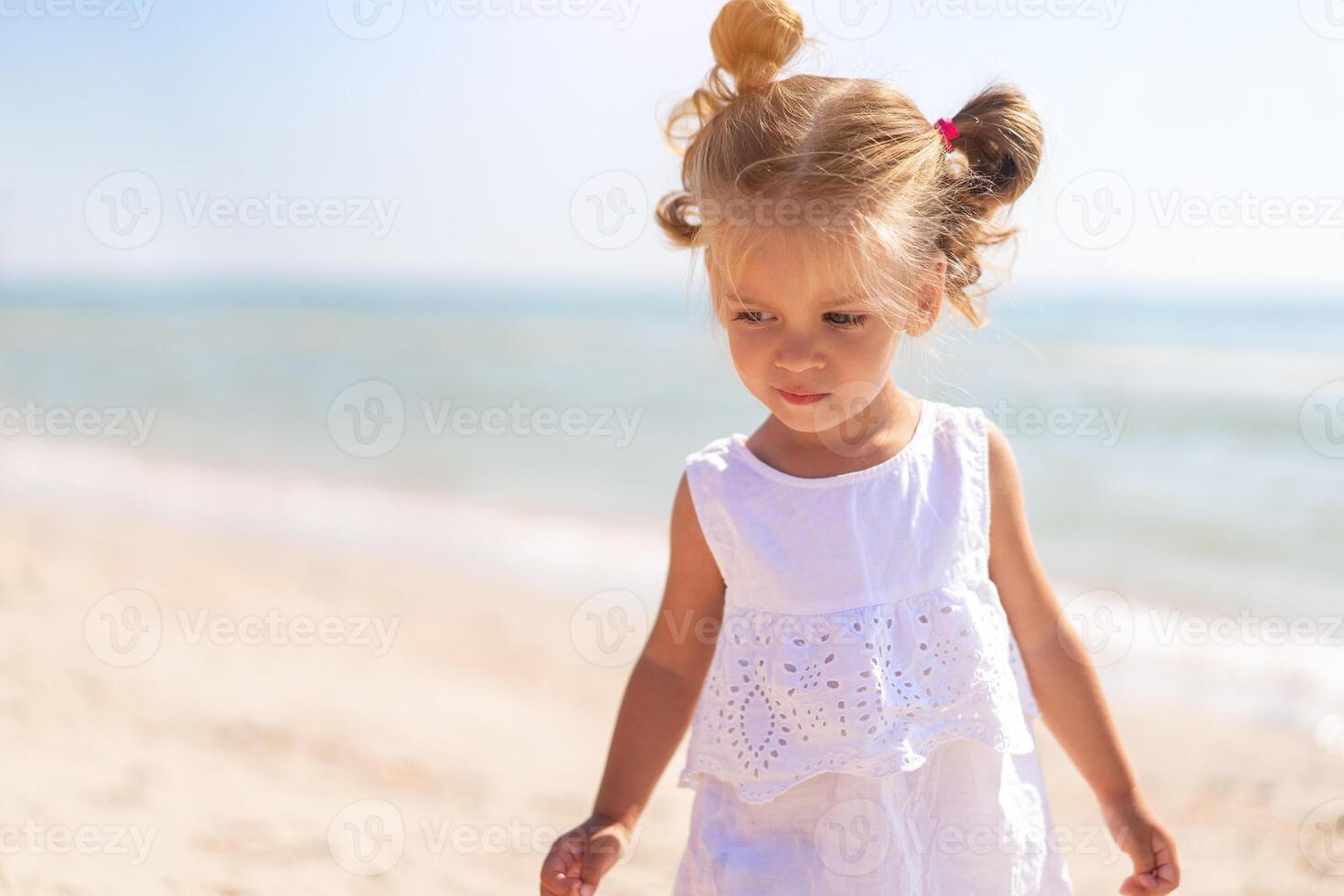 Little Caucasian girl 3 years old walks along the sea coast. Cute child portrait on the beach. Family vacation photo