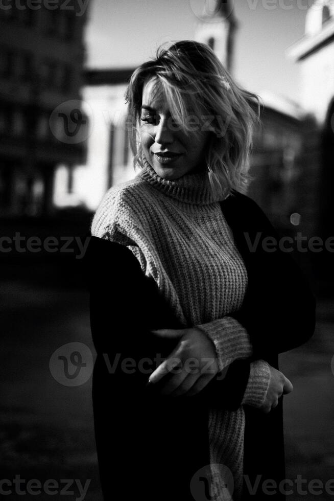 Confident Woman in Sweater Stands with Arms Crossed in Front of Building. Stylish Female Portrait. Urban Lifestyle Concept with Fashionable Woman in City Setting photo