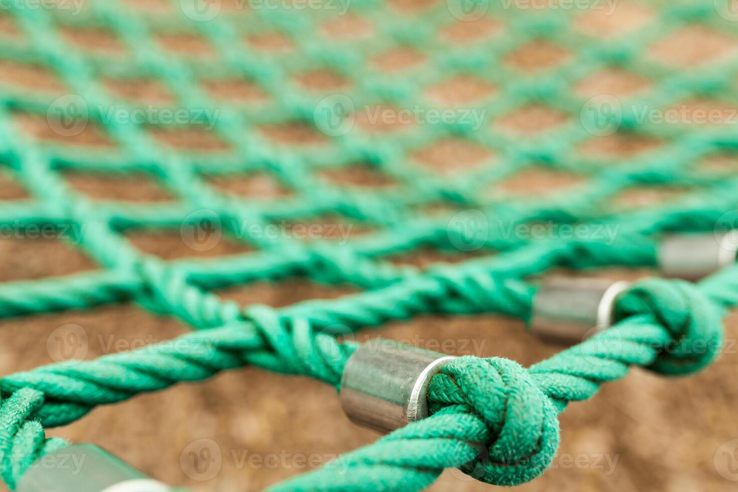 Rope mesh with blurry background. It is a green rope mesh in a playground. It is not a brand new rope mesh but it is old and deteriorate. photo