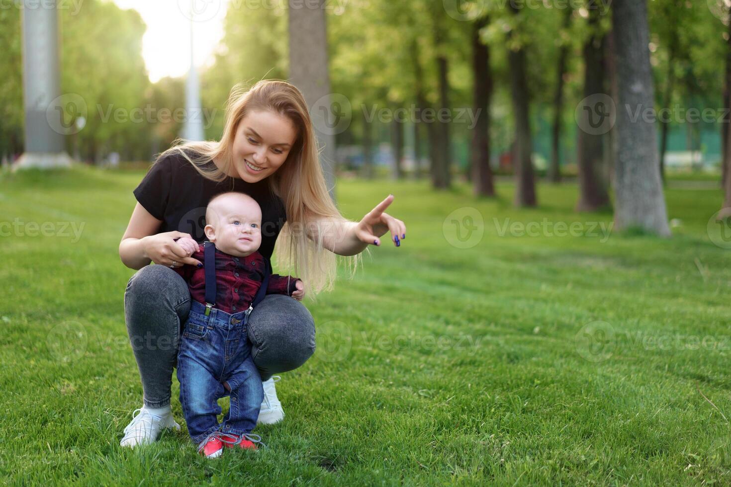 Beautiful young mother walks with her little son in a summer park photo