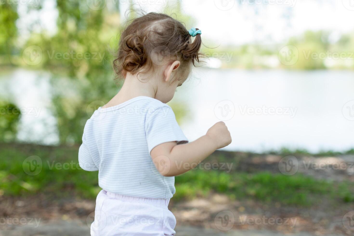 little girl walking and playing outside near lake photo
