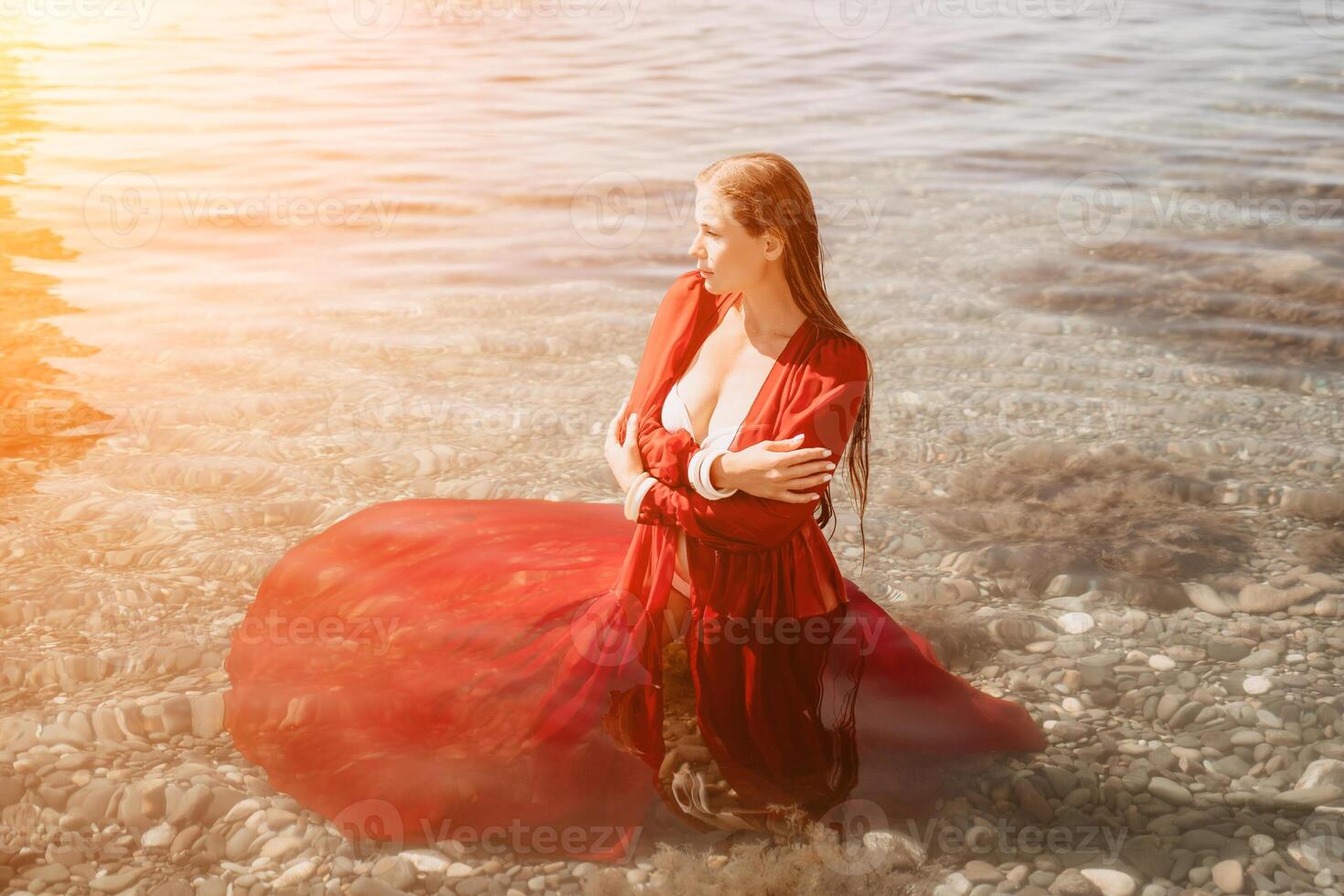 Woman travel sea. Happy tourist in red dress enjoy taking picture outdoors for memories. Woman traveler posing in sea beach, surrounded by volcanic mountains, sharing travel adventure journey photo