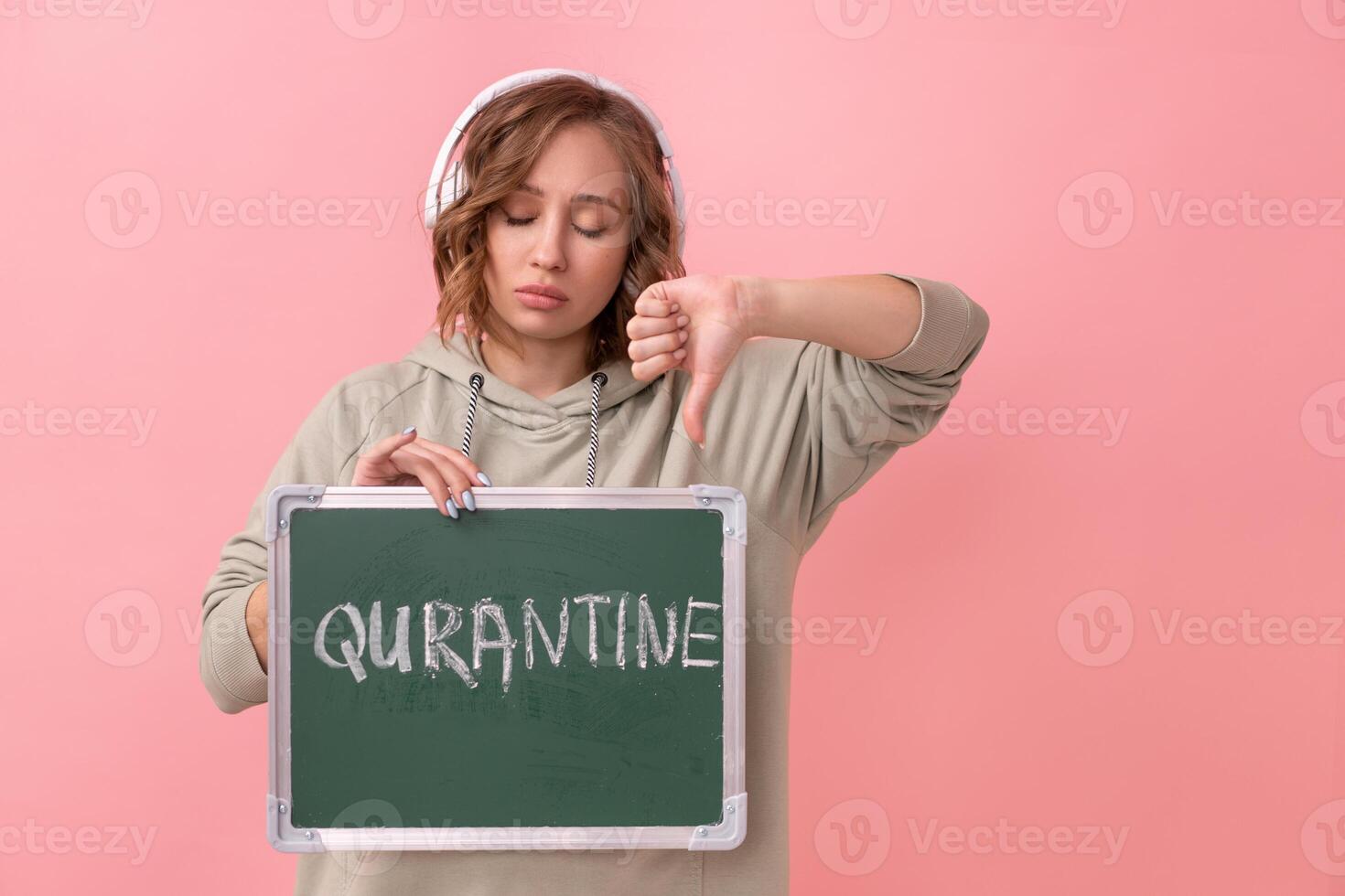 Stay home concept Woman with headphones dressed oversize hoodie holds chalkboard with the words quarantine photo