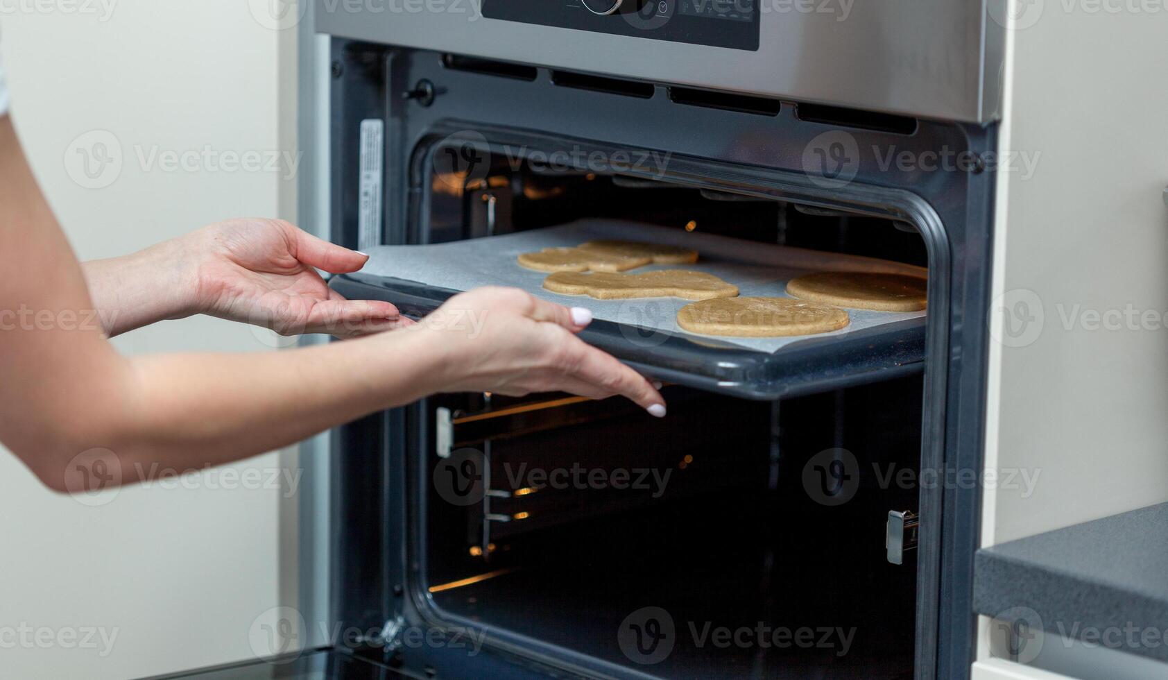 Woman put raw dough in oven in kitchen closeup. photo