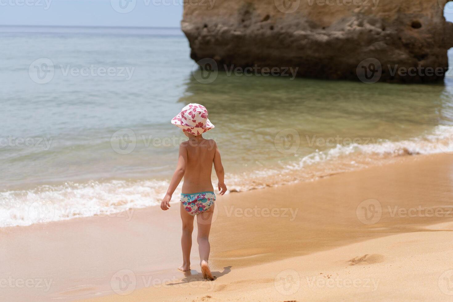 Back view of adorable little girl at sandy Atlantic ocean beach during summer photo