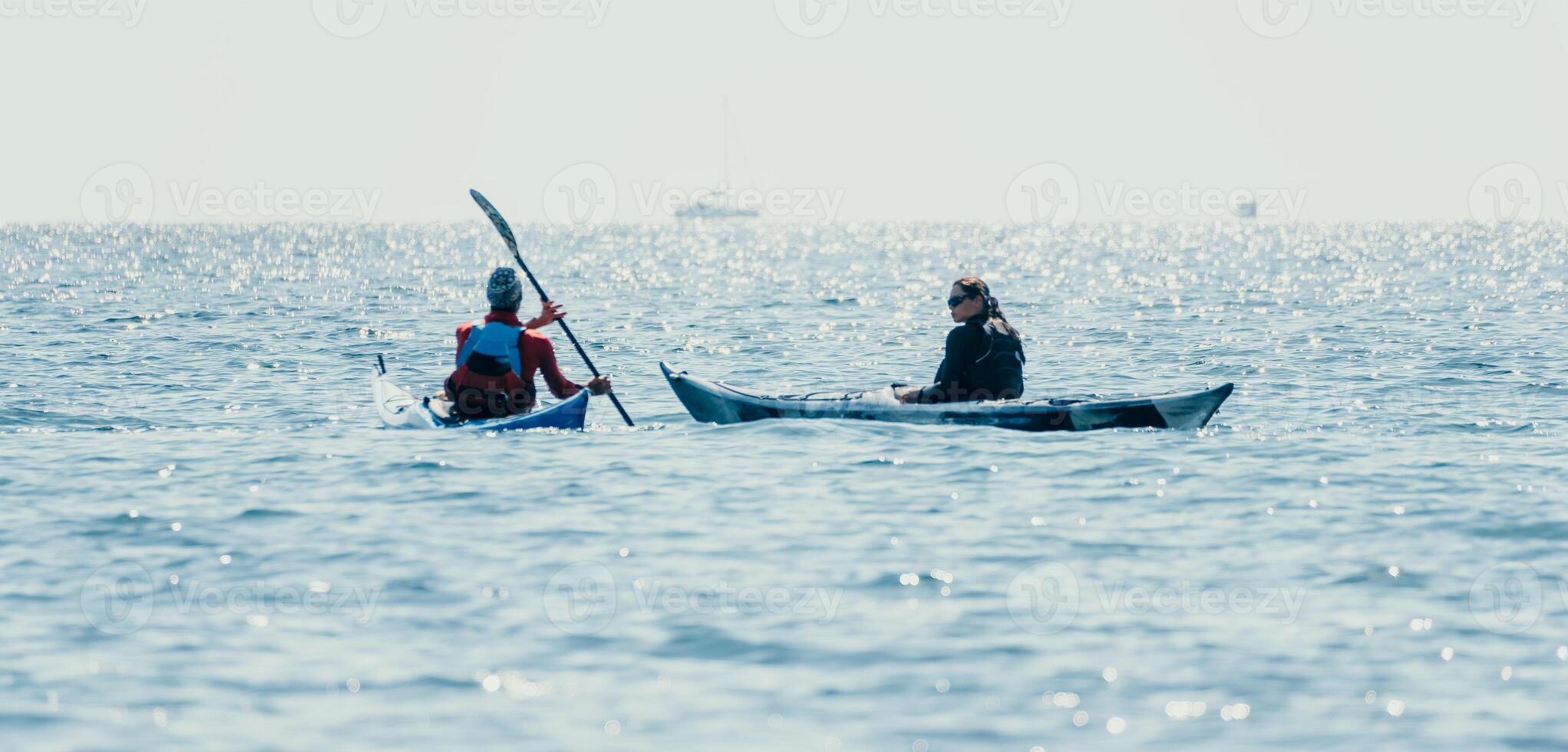 Man woman sea kayak. Happy free man and woman in kayak on ocean, paddling with wooden oar. Calm sea water and horizon in background. Active lifestyle at sea. Summer vacation. photo