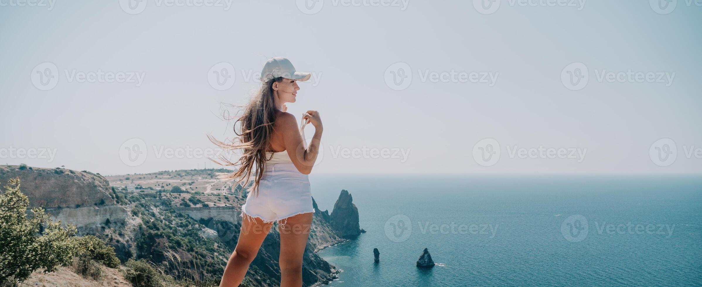 mujer verano viaje mar. contento turista disfrutar tomando imagen al aire libre para recuerdos. mujer viajero posando terminado mar bahía rodeado por volcánico montañas, compartiendo viaje aventuras viaje foto