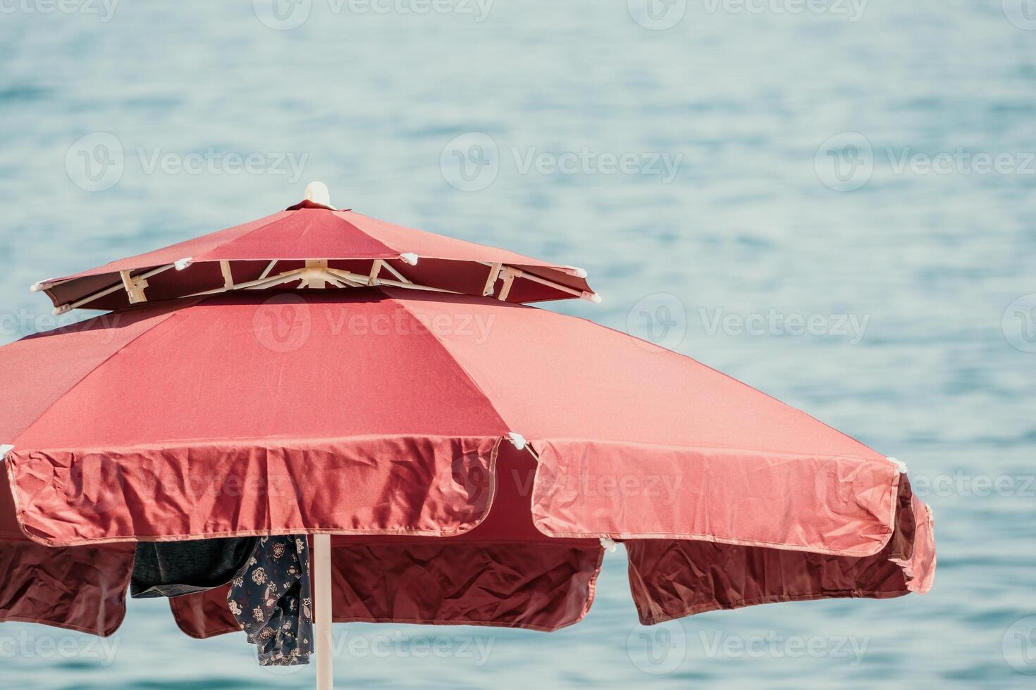 Red Beach Umbrella on the Background of the Blue Sea Ocean. Beach Landscape. Summer travel and holidays concept. photo