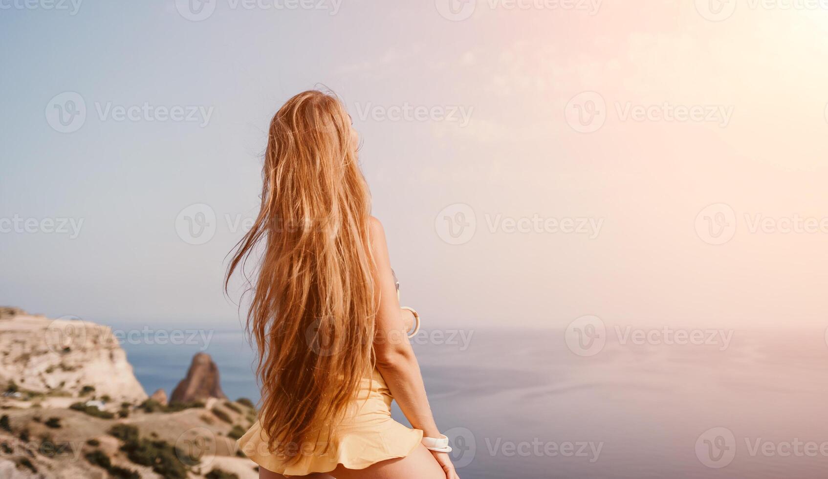 Woman travel sea. Happy tourist taking picture outdoors for memories. Woman traveler looks at the edge of the cliff on the sea bay of mountains, sharing travel adventure journey photo