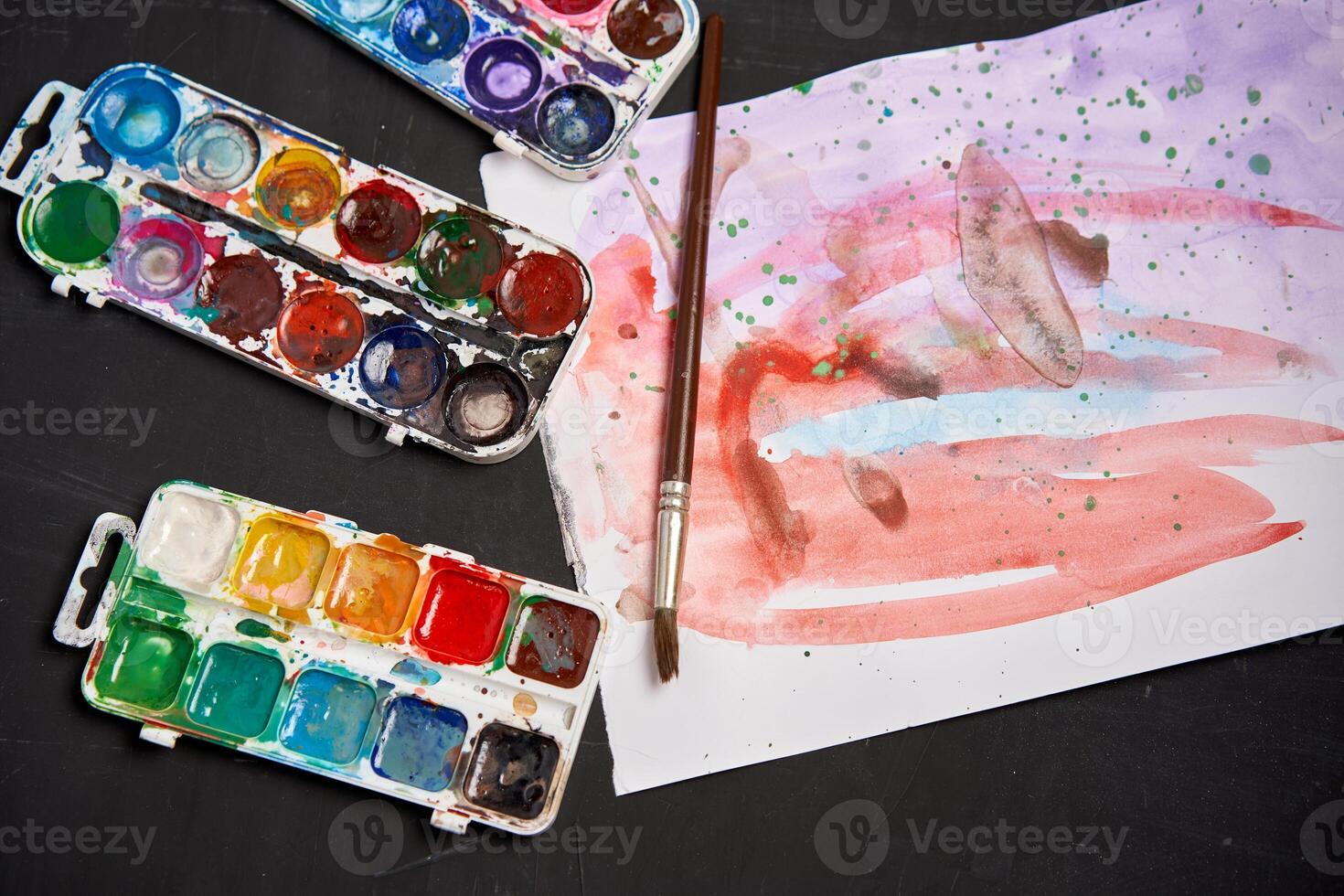 Set of watercolor paints on a black background. Brushes drawing. Creative background. School for teaching drawing. photo