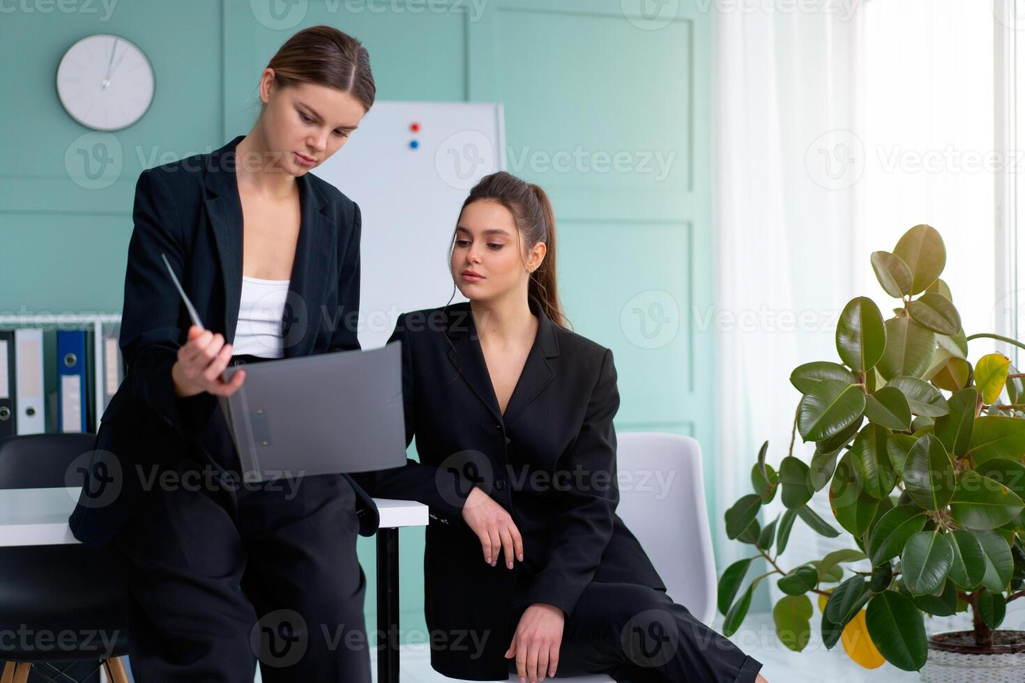 Young women leaders are checking financial statements from paper documents. Two female confident business worker dressed black suit in office checking financial document photo