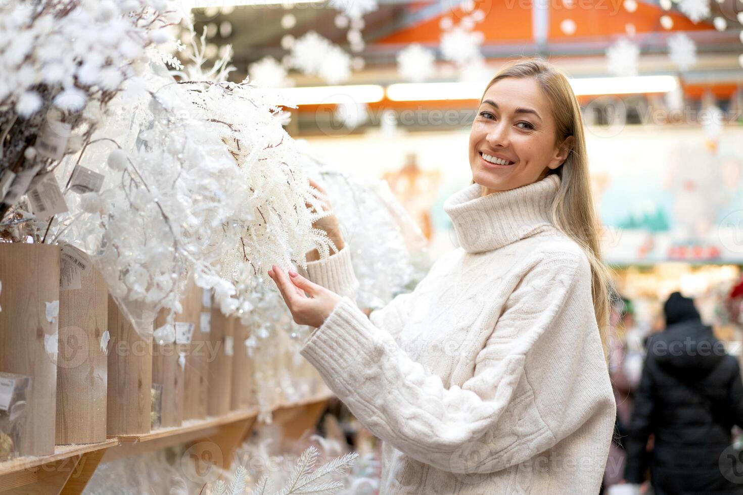 Navidad compras, europeo mujer escoger ramas para Navidad guirnalda interior en supermercado. caucásico hembra comprando foto