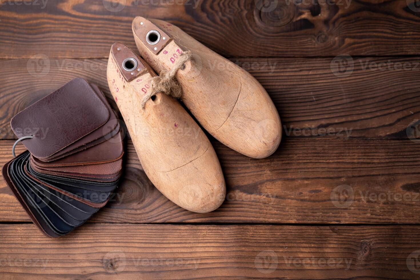 Leather samples for shoes and wooden shoe last on dark wooden table. photo