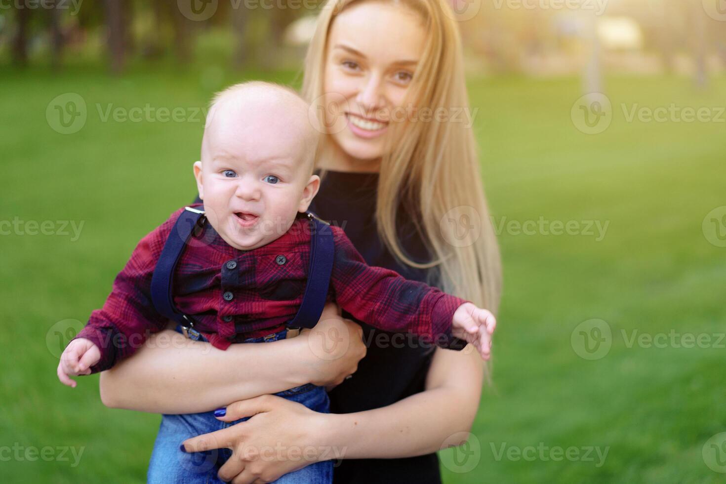 Beautiful young mother walks with her little son in a summer park photo