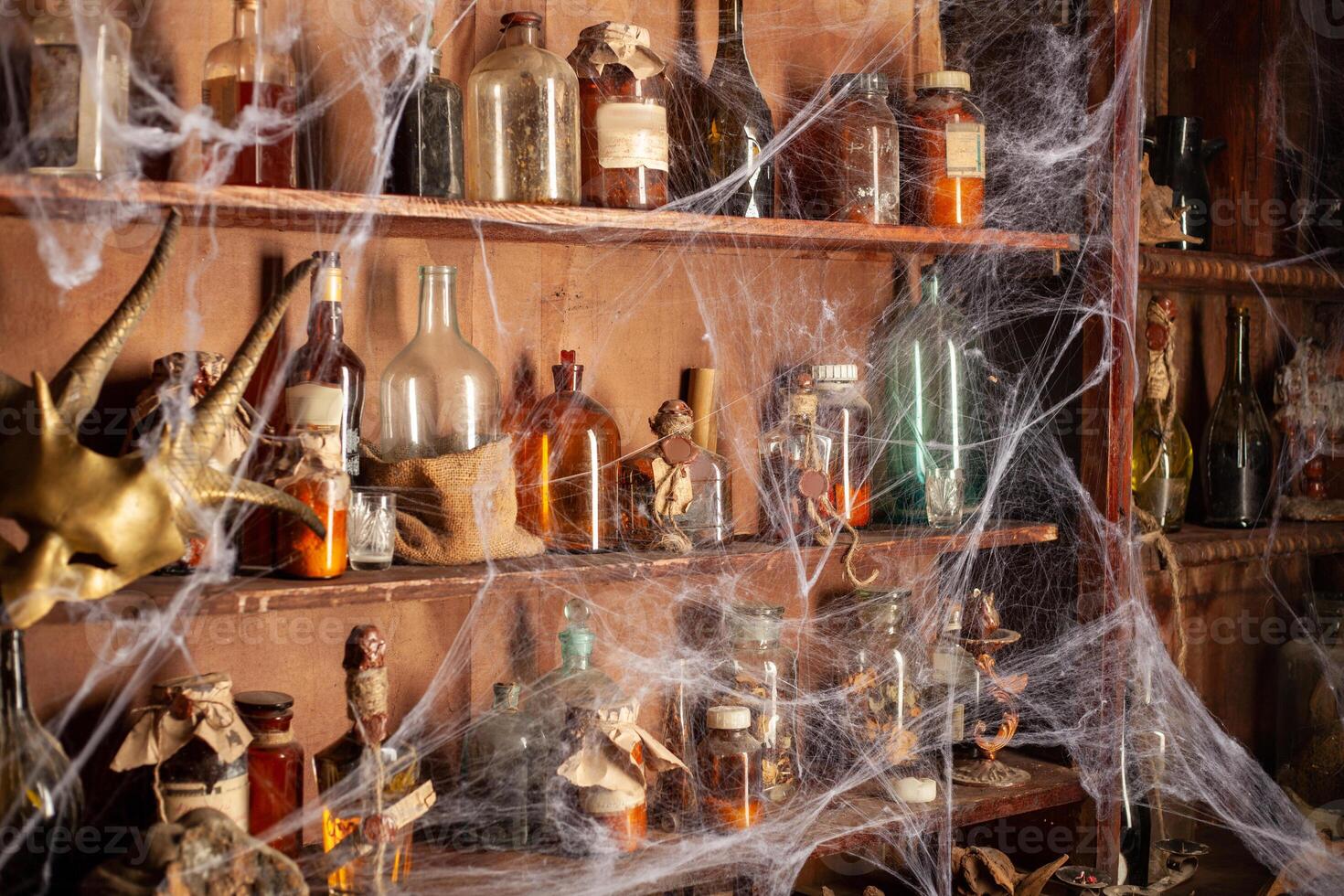 Halloween background Shelves with alchemy tools Skull spiderweb bottle with poison candles photo
