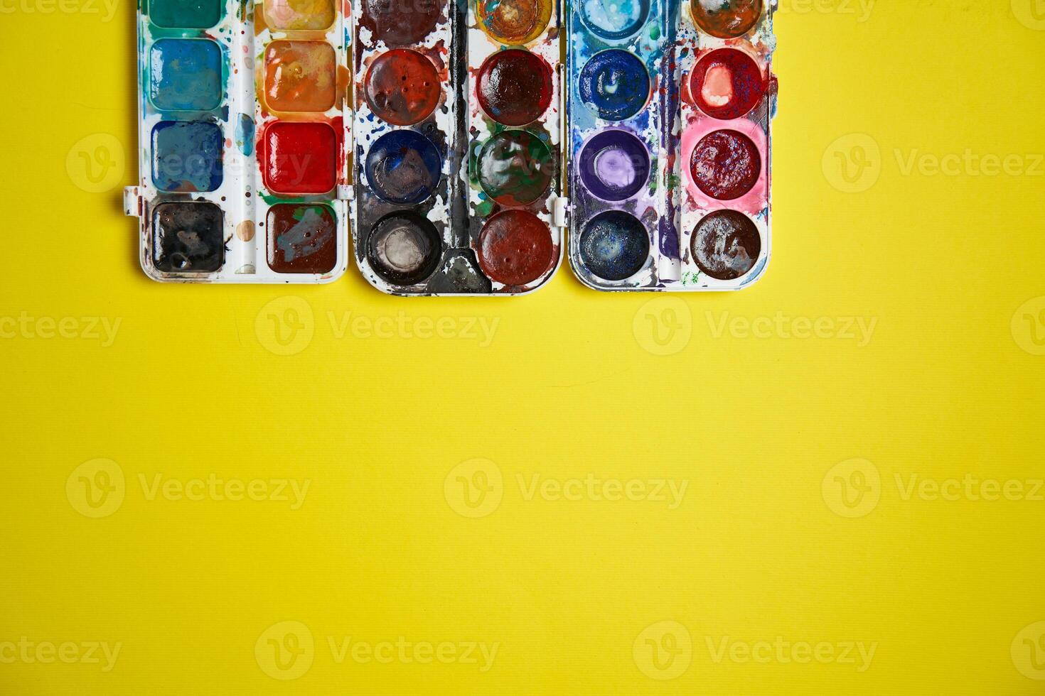 Set of watercolor paints on yellow background. Brushes drawing. Creative background. School for teaching drawing. photo