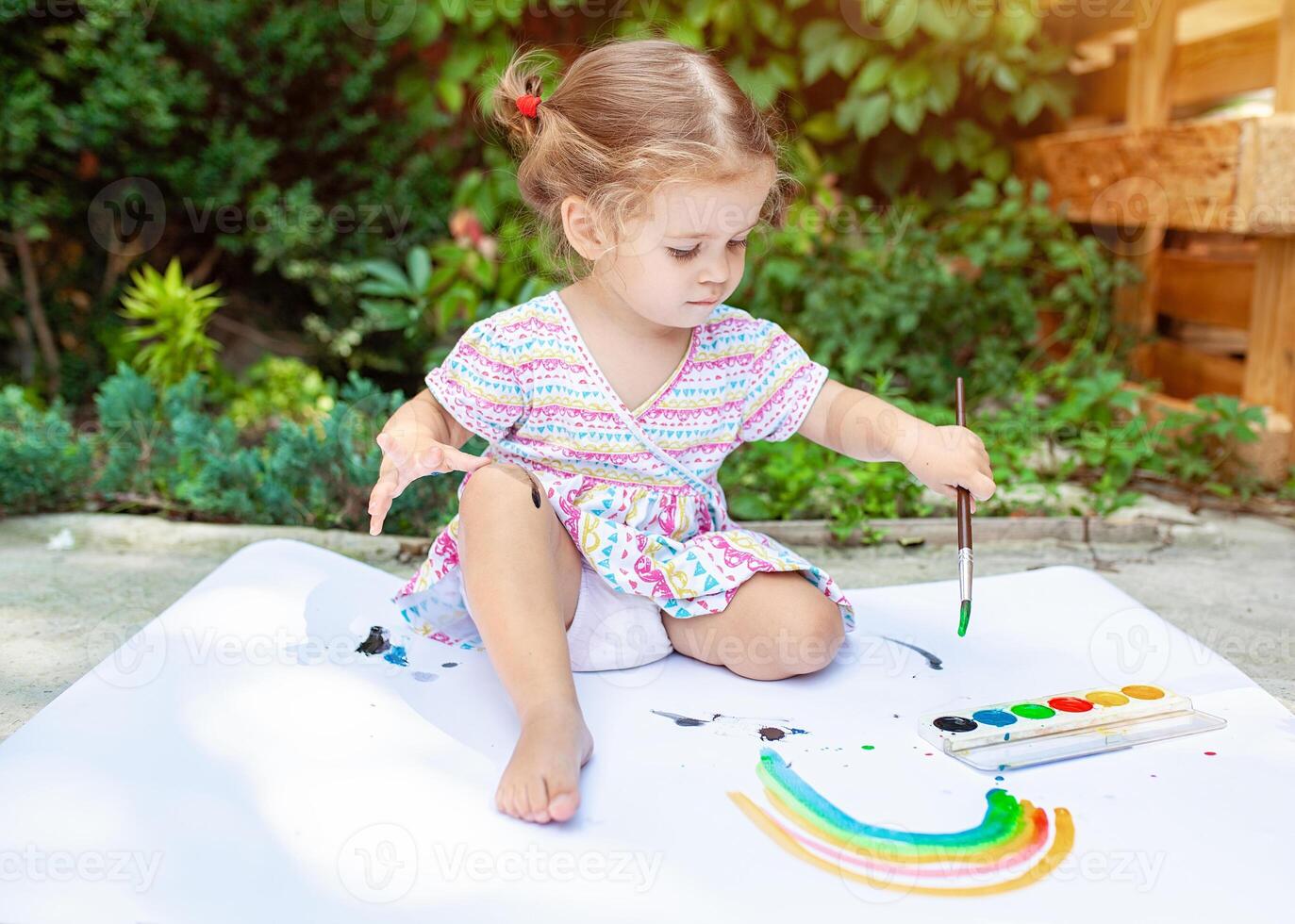 Portrait of little blonde girl painting, summer outdoor. photo