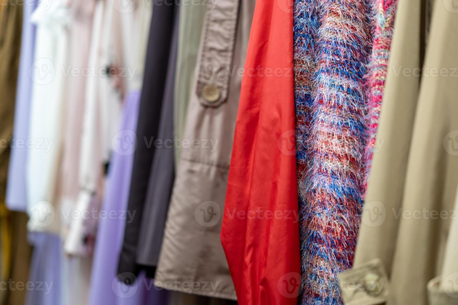 Multi colored clothing shirts hang on hangers in a shop background. A variety of clothes  hanging in the wardrobe. photo