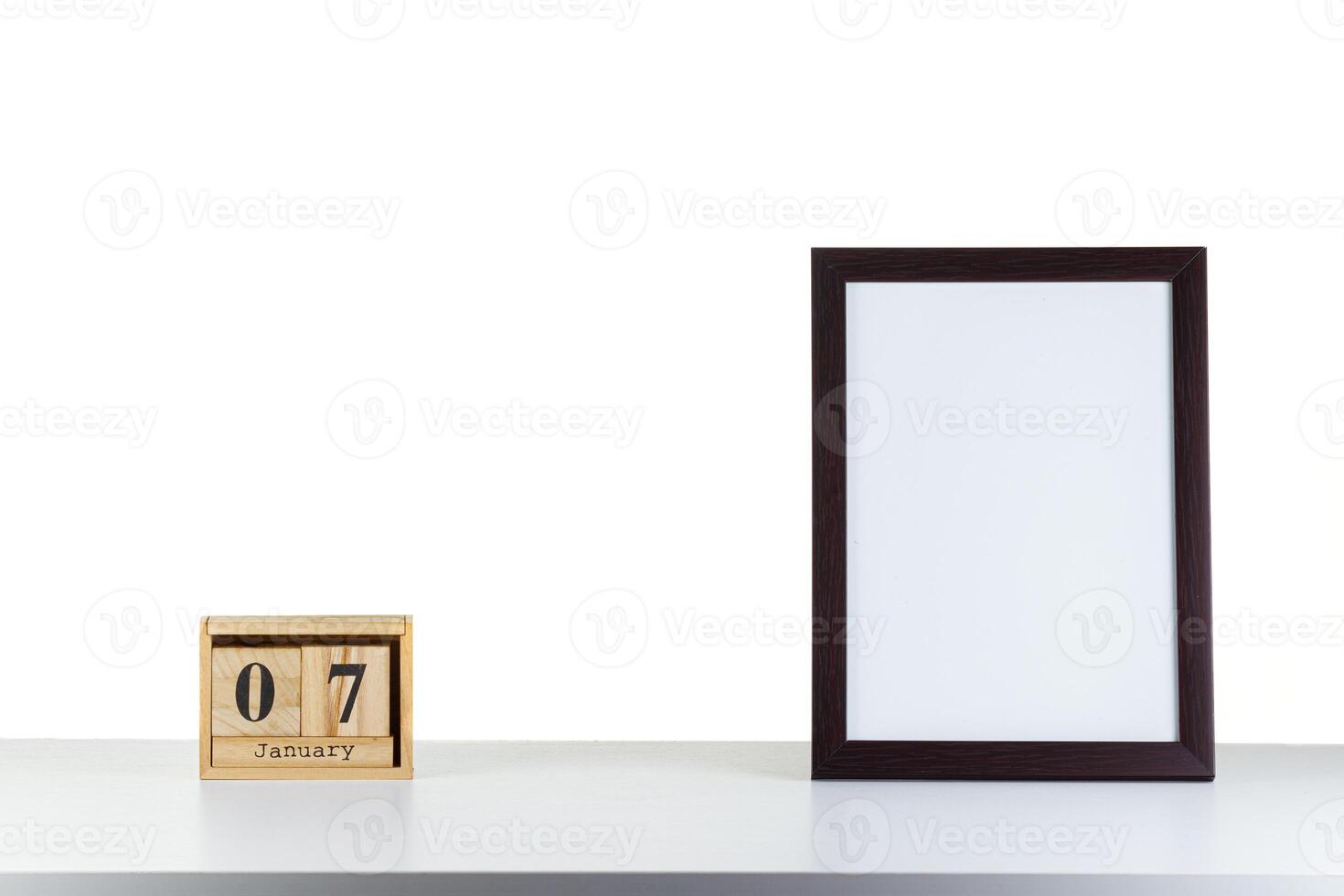 Wooden calendar 07 January with frame for photo on white table and background