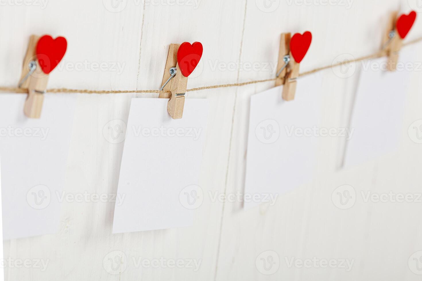 white pieces of paper on clothespins with a heart on a wooden background photo