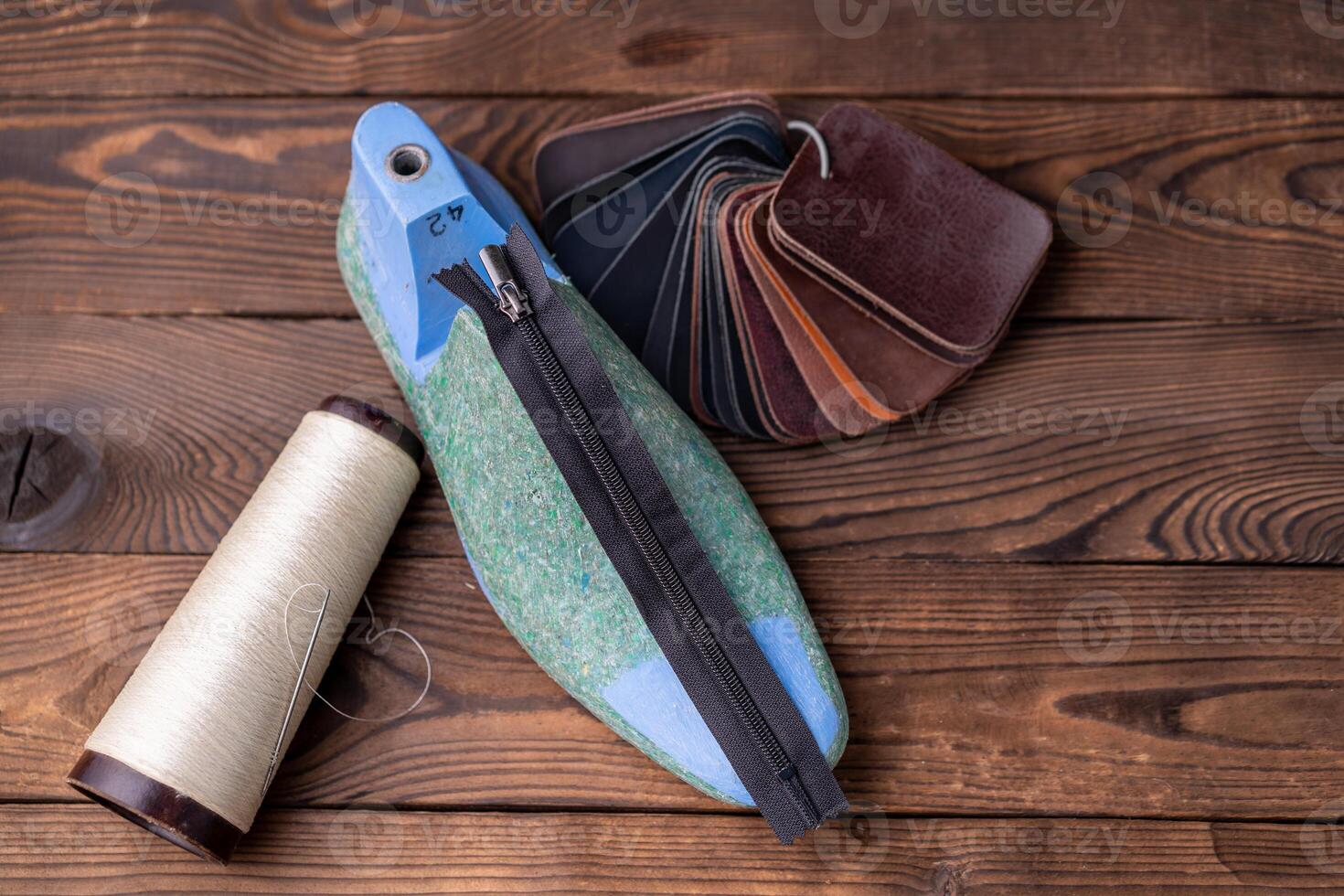 Leather samples for shoes and plastic shoe last on dark wooden table. photo