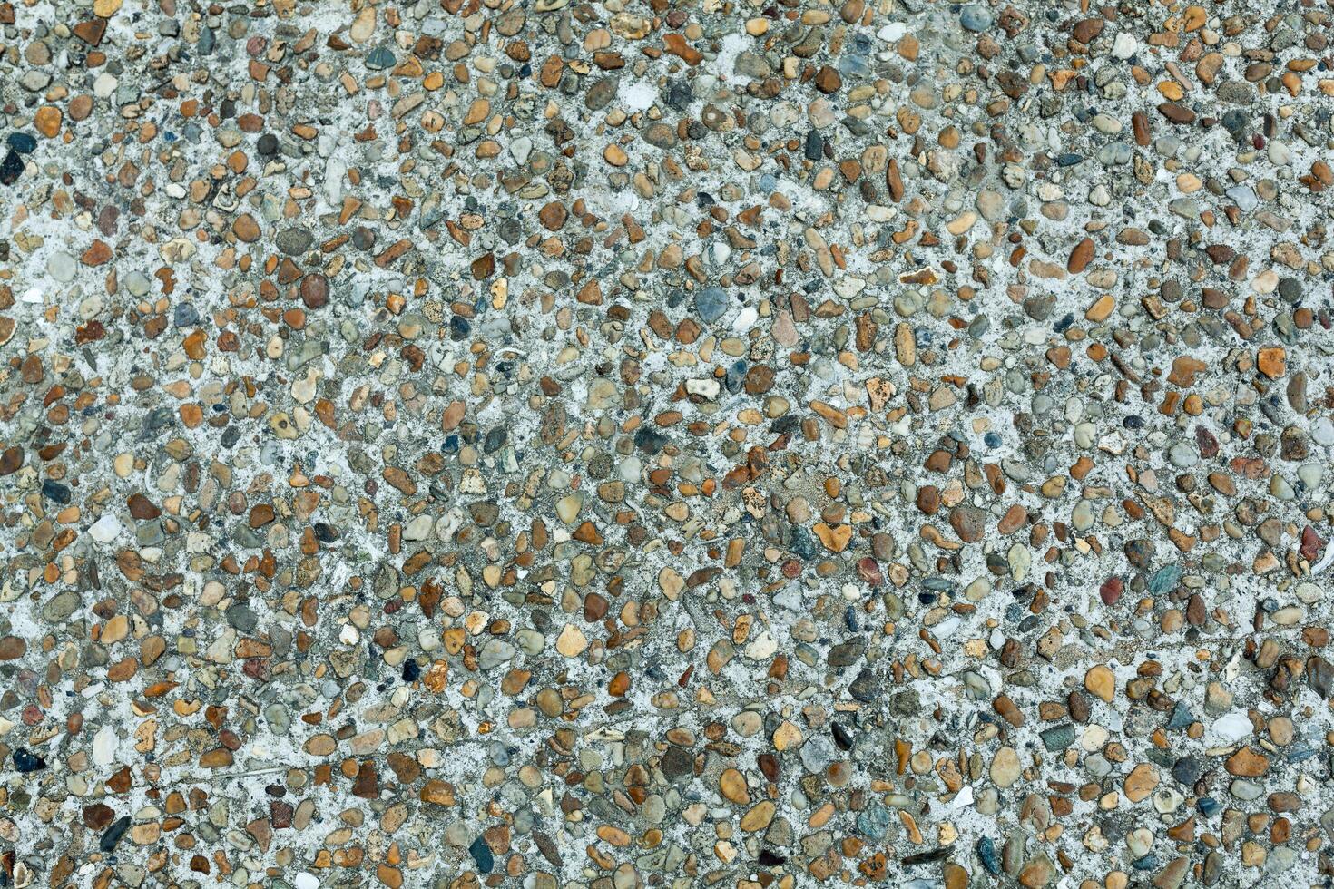 Pebble stone floor tile seamless background. Cement mixed gravel pebble stone floor texture. Wet round pebble stone rock floor in dramatic lighting. photo