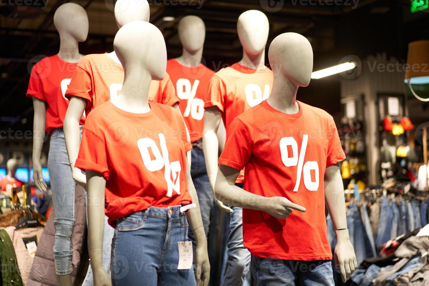 Percentage sign painted on a red t-shirt dressed on a mannequin stands in defocused store photo