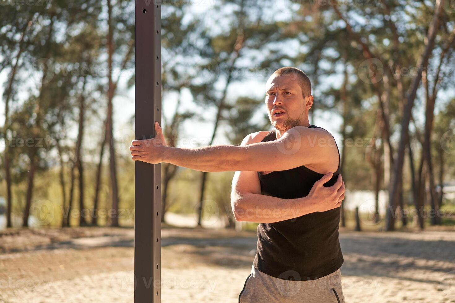 Handsome men outdoor workout cross training morning workout. Stretching arm before exercising outside sports ground nature forest photo