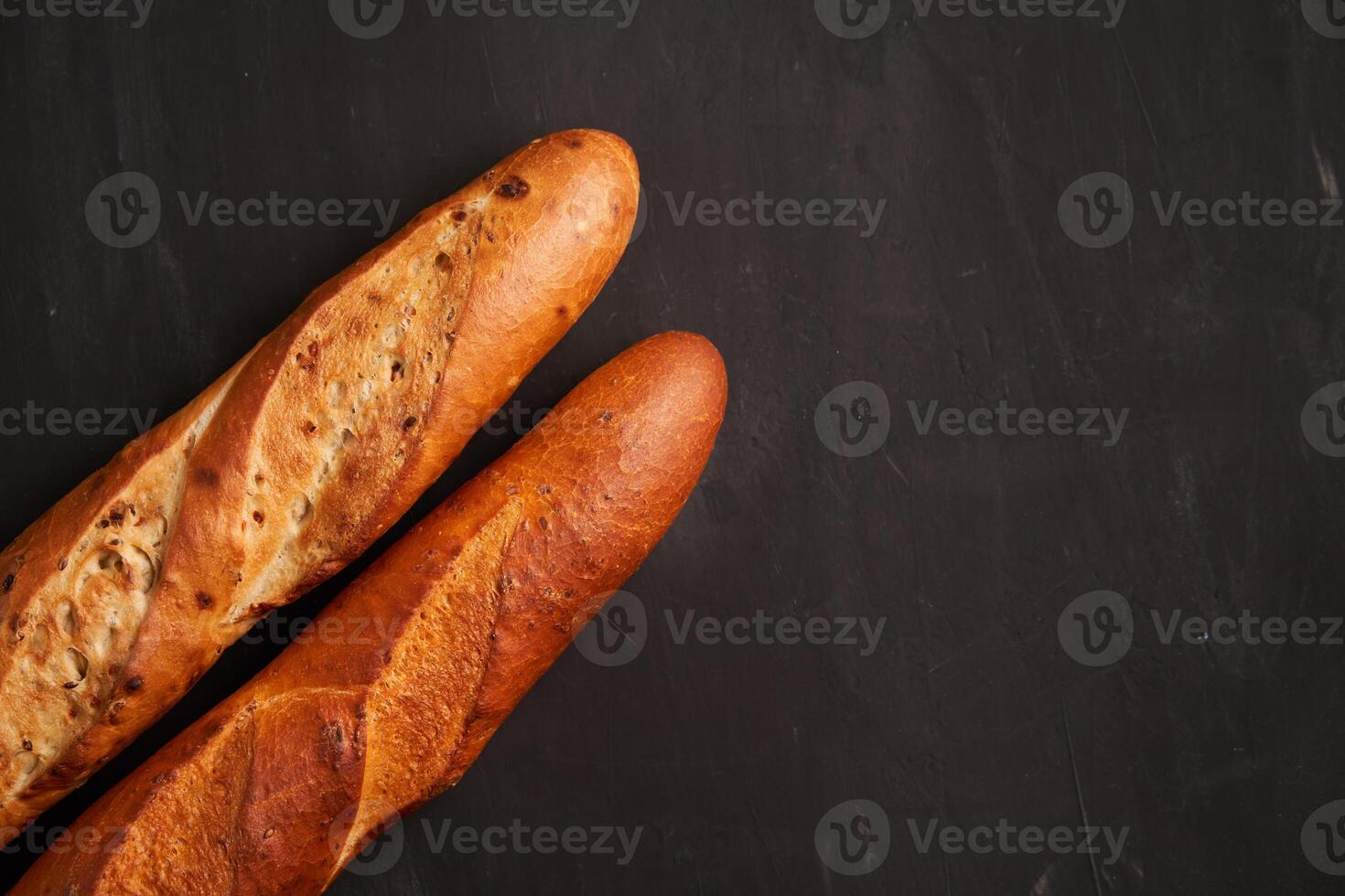 Two crispy french baguettes lie on an old wooden table with free space for text photo