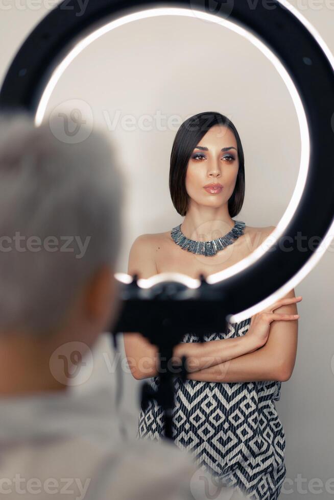 Makeup artist bsn photographs on a mobile phone the result of his work on a beautiful girl model with a ring light lamp photo