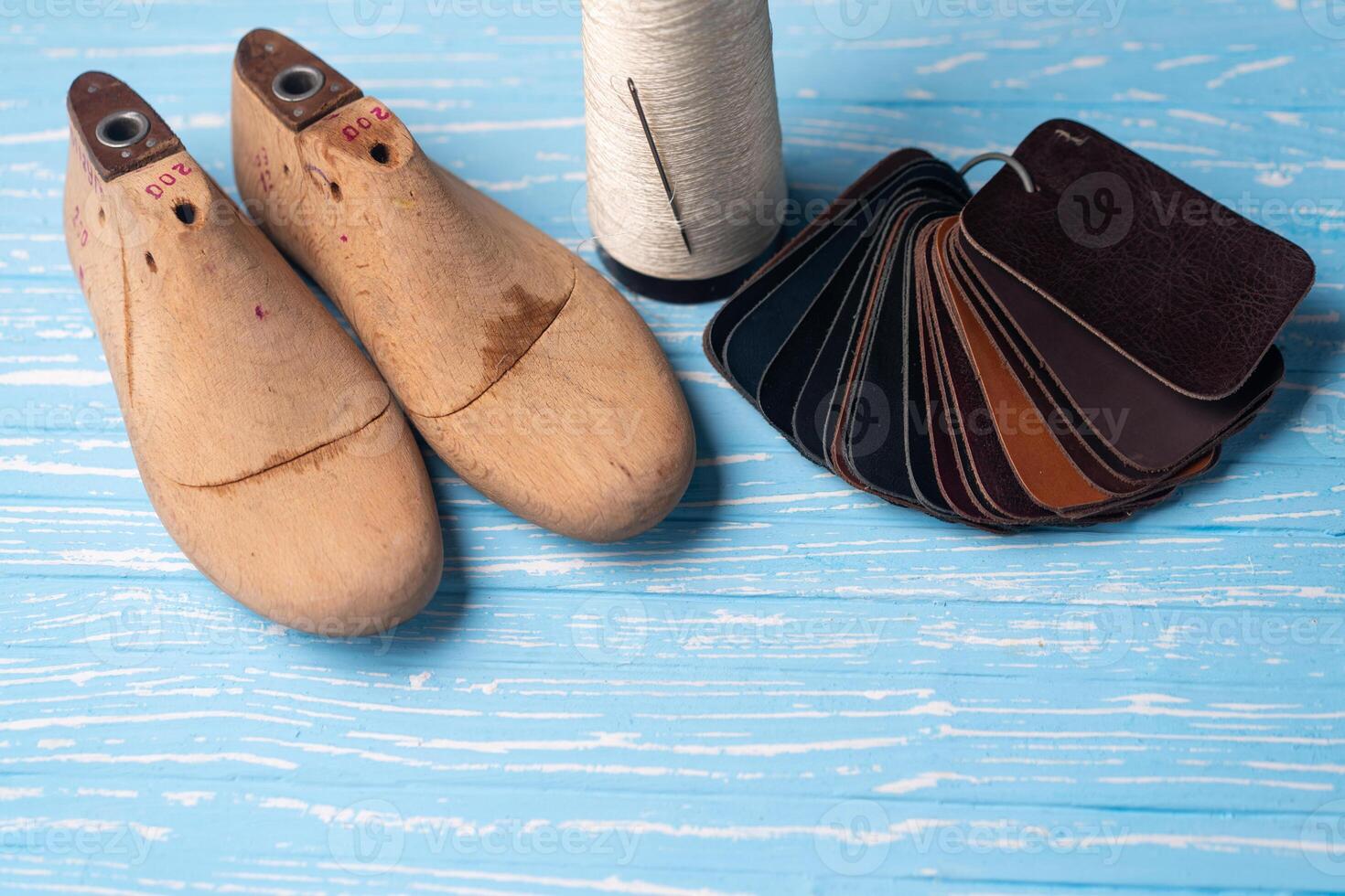 Leather samples for shoes and wooden shoe last on blue wooden table. photo