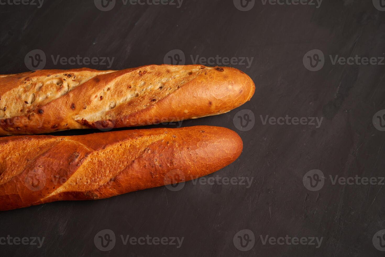 Two crispy french baguettes lie on an old wooden table with free space for text photo