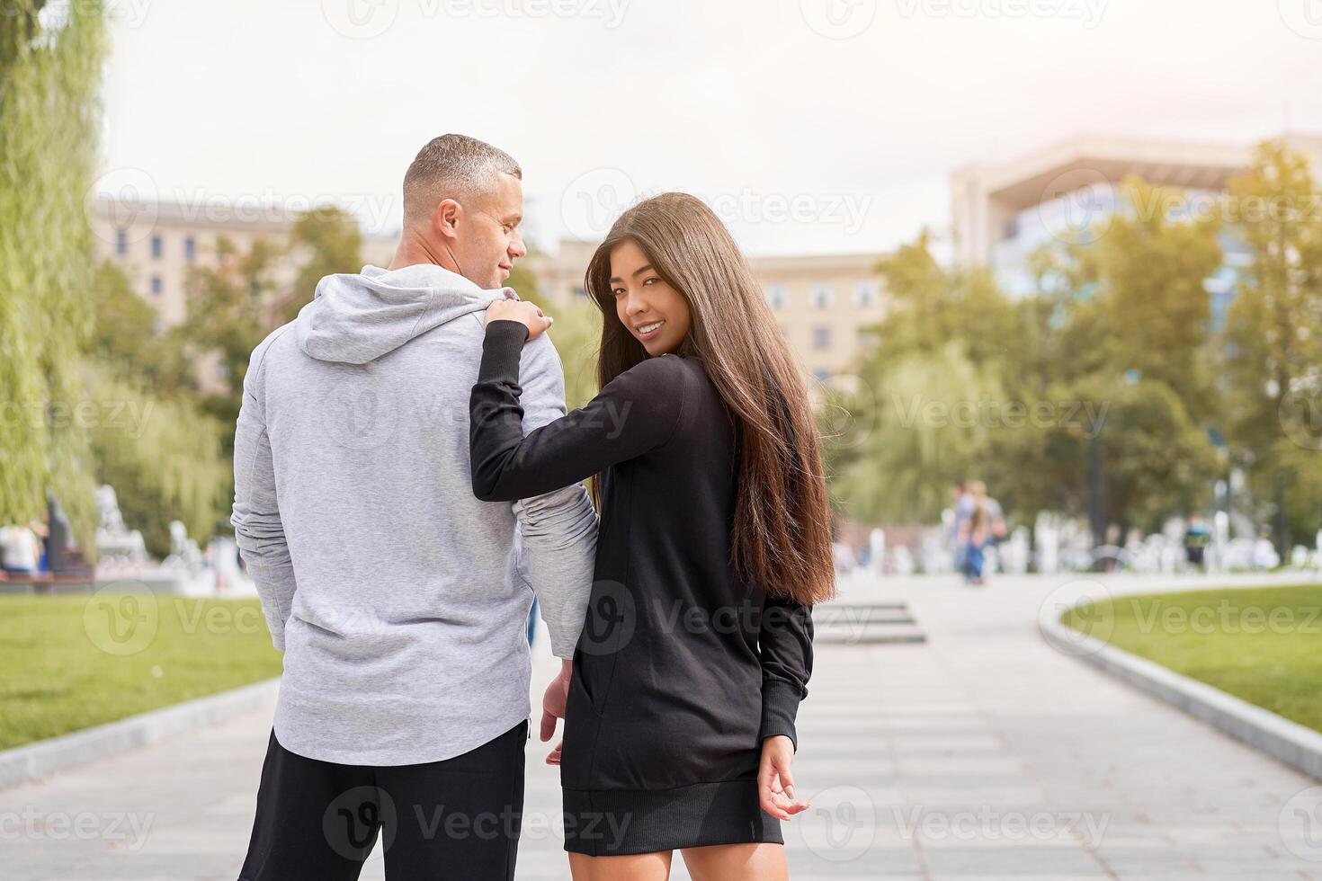 Couple in love walking outdoors park fountain Caucasian man asian woman walk outside dressed sport clothes photo