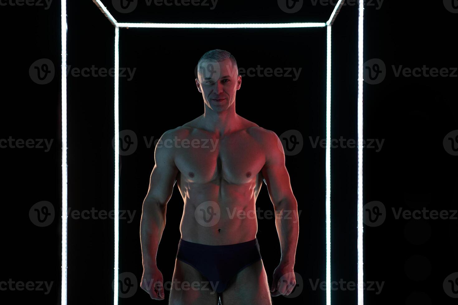 Active lifestyle concept. Professional bodybuilder showing perfect muscular body, lamps illumination on background photo