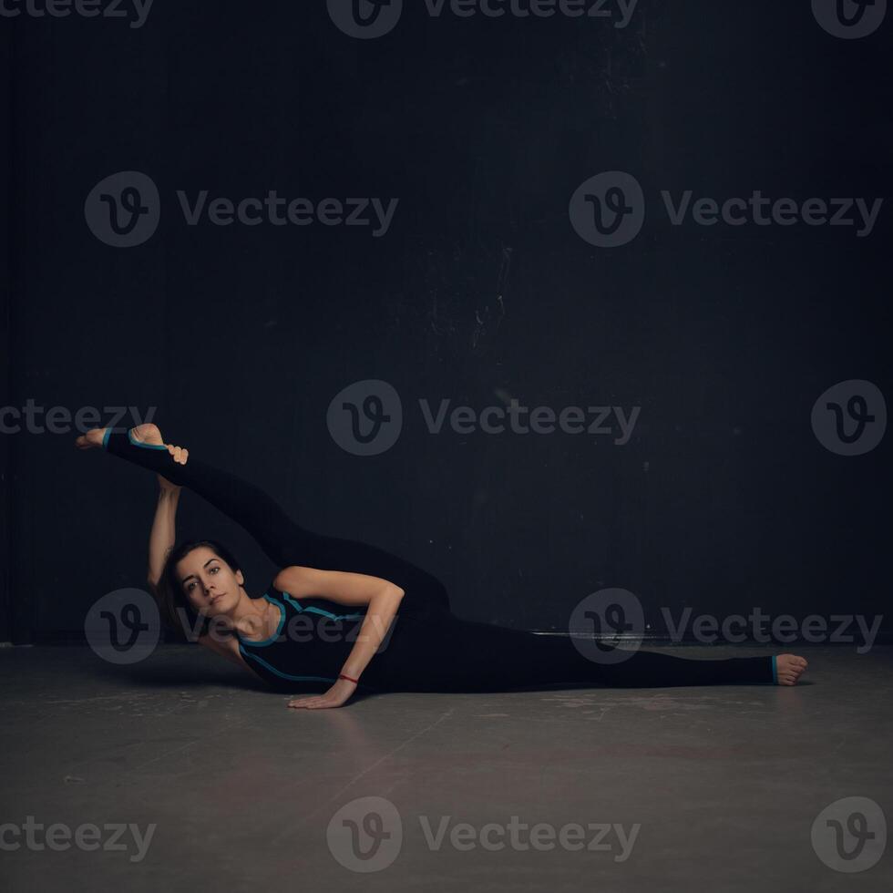 Woman practicing yoga against a dark texturized wall photo