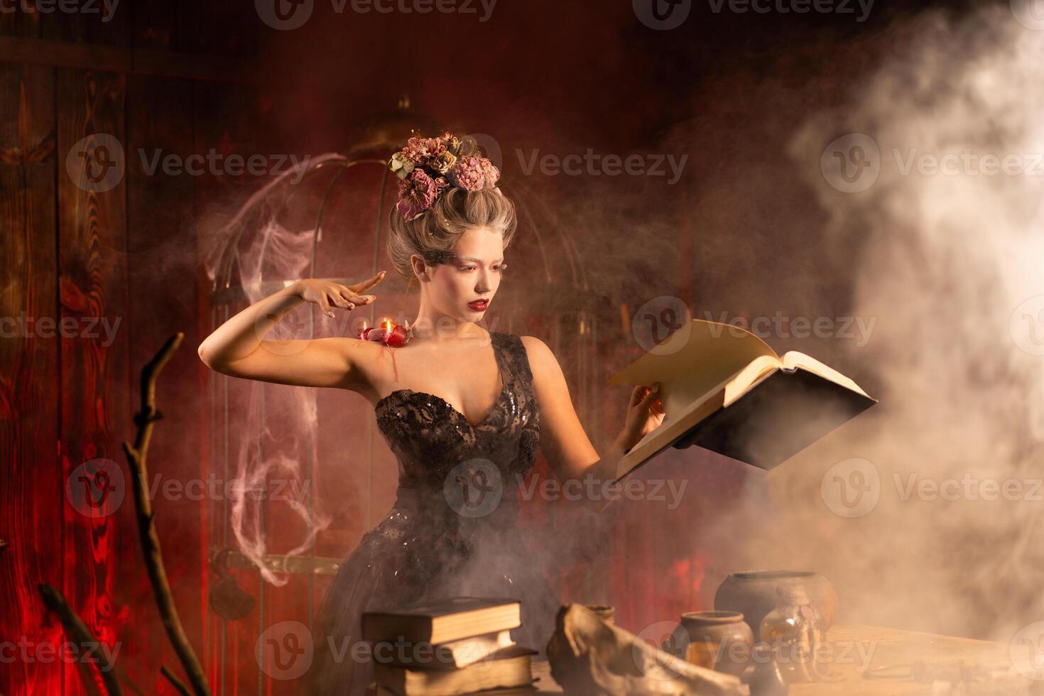 Charming woman witch flowers in hair vintage black dress with book of spell in the old castle. Halloween. Celebration. photo