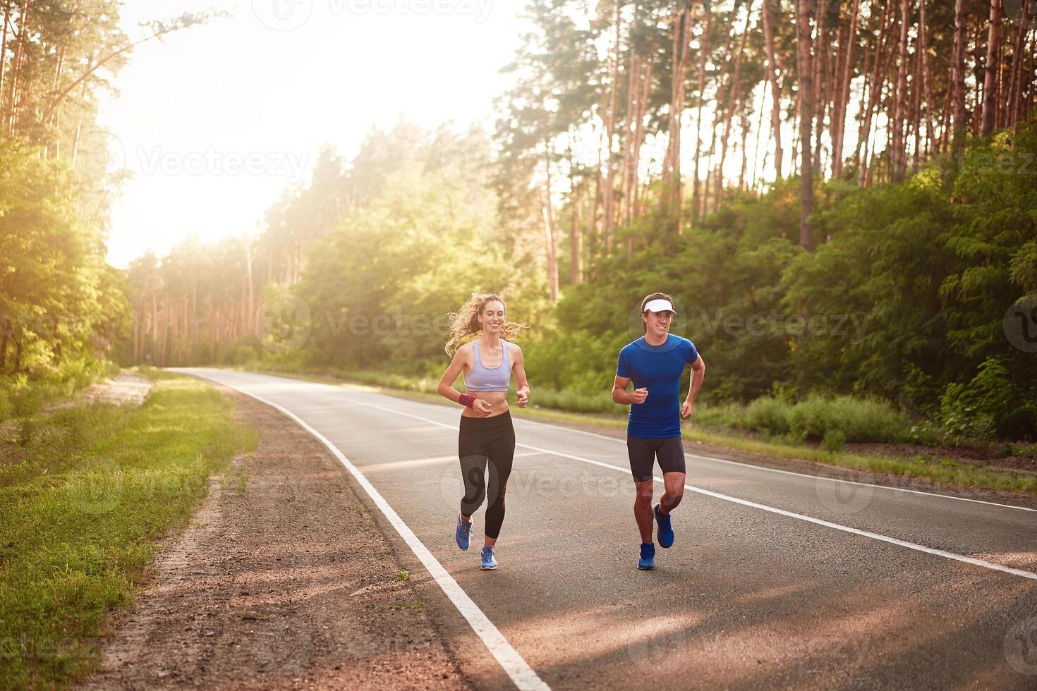 Caucasian female sports woman and fit man in full body length running pine forest road. healthy lifestyle concept photo