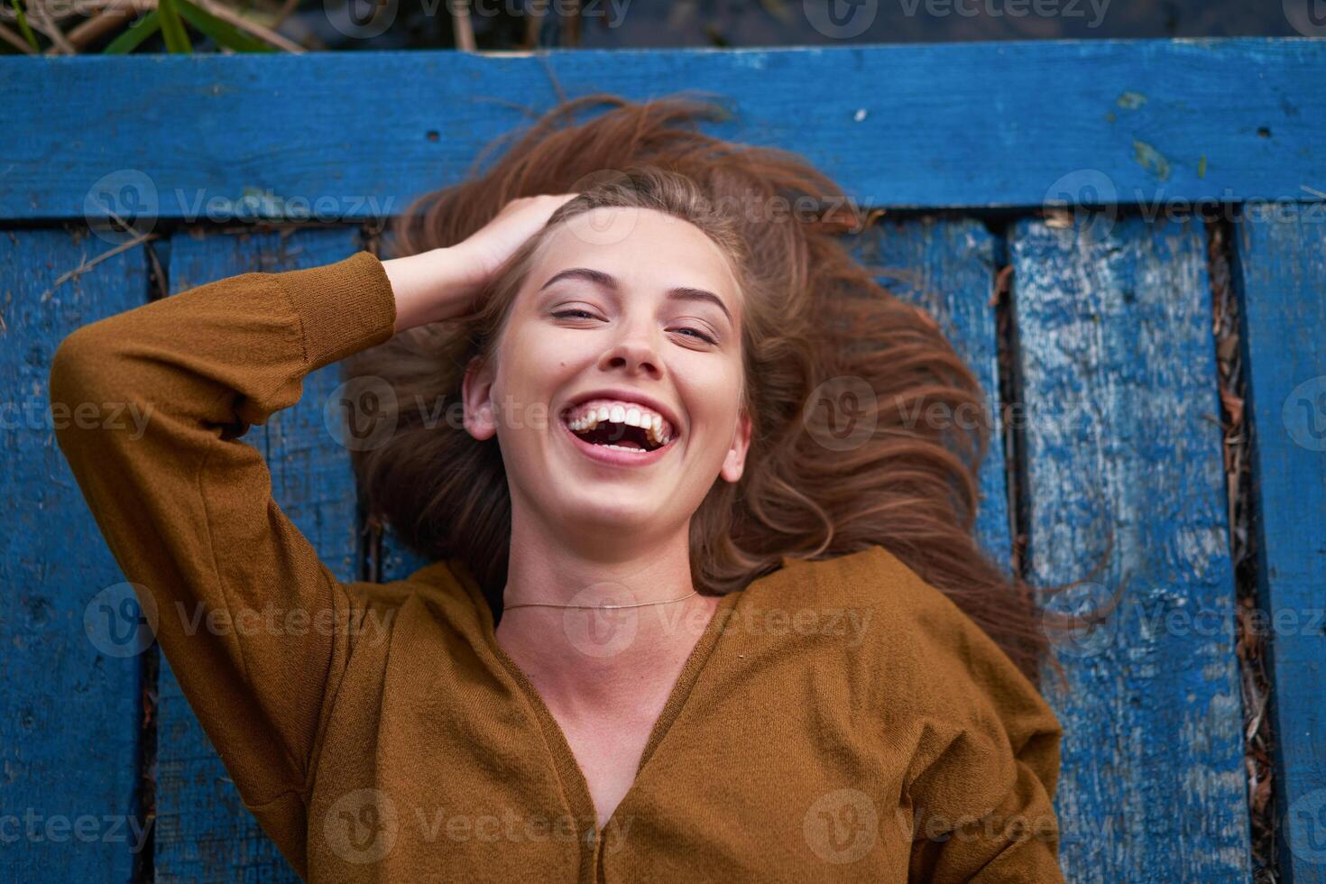 Beautiful caucasian young woman Lying on her back on wooden background. photo