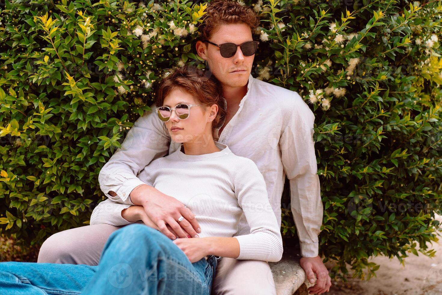 Young beautiful hipster couple in love sitting on old city park photo