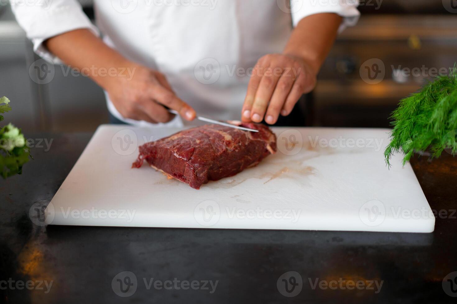 unrecognizable young African chef standing in professional kitchen in restaurant preparing a meal of meat and cheese vegetables. photo