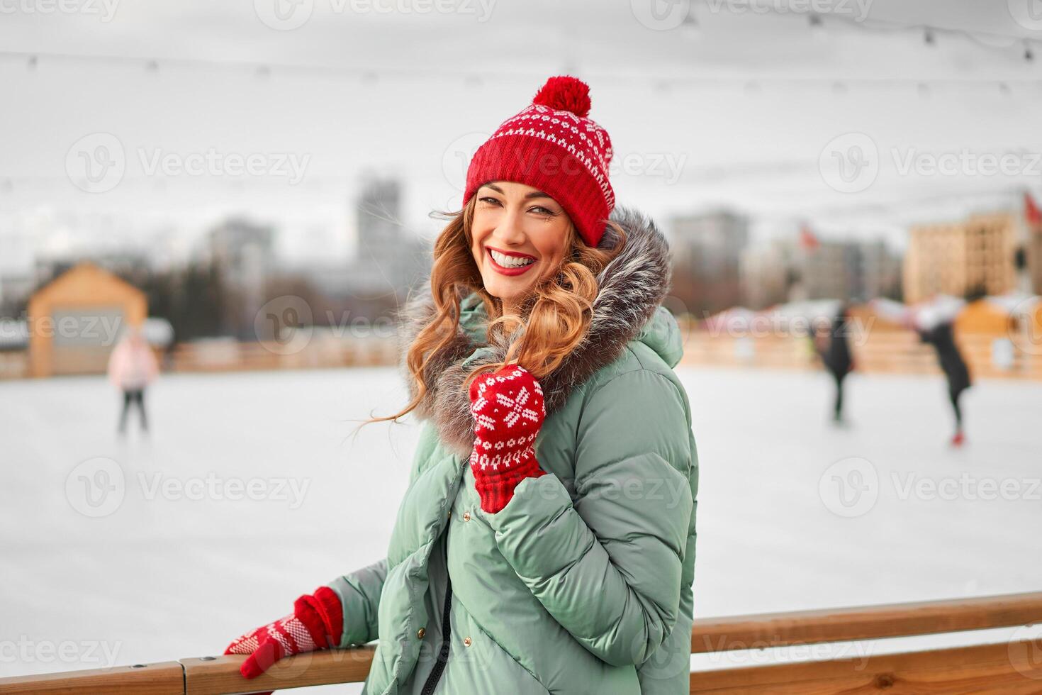 Beautiful lovely middle-aged girl with curly hair warm winter jackets stands ice rink background Town Square. photo