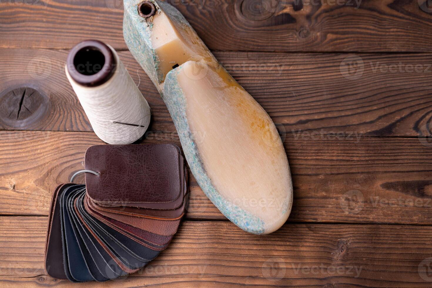 Leather samples for shoes and plastic shoe last on dark wooden table. photo