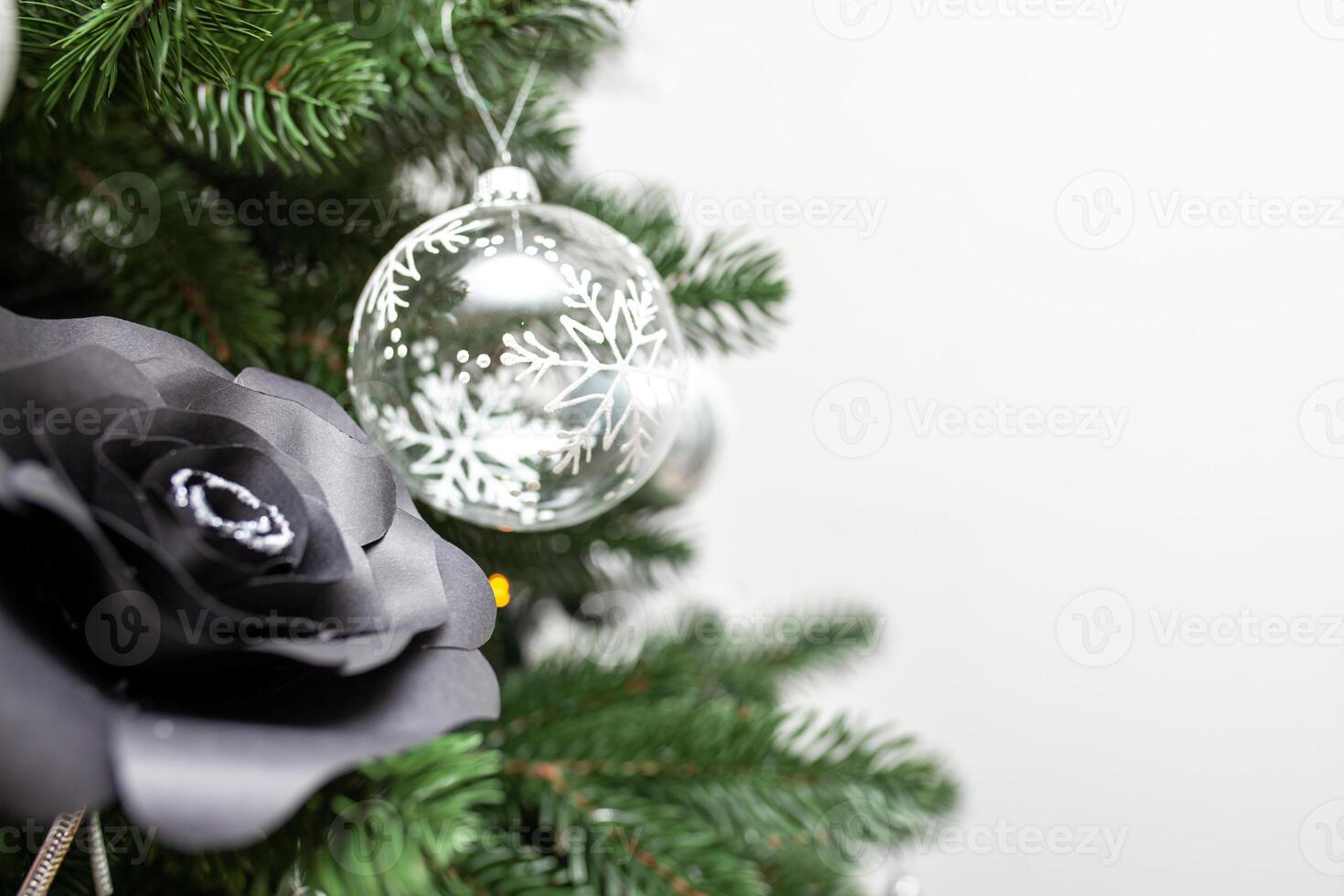 Close-up of a Christmas tree decorated with transparent balls and black paper roses. Christmas holiday concept photo