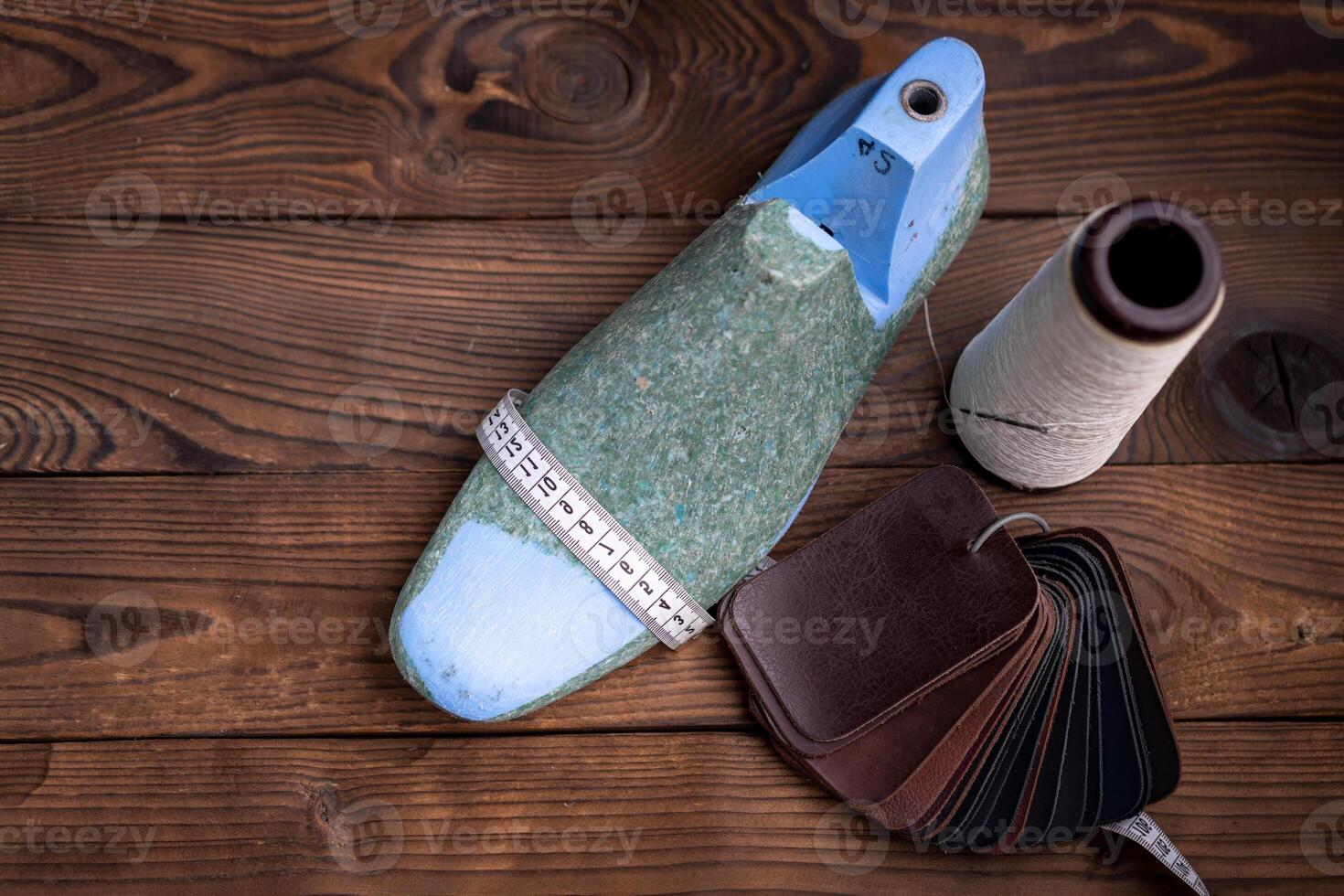 Leather samples for shoes and plastic shoe last on dark wooden table. photo